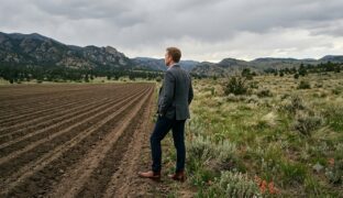 Man standing between the wilds and a cultivated field
