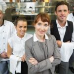 Nice female manager posing with the staff in a modern kitchen catering