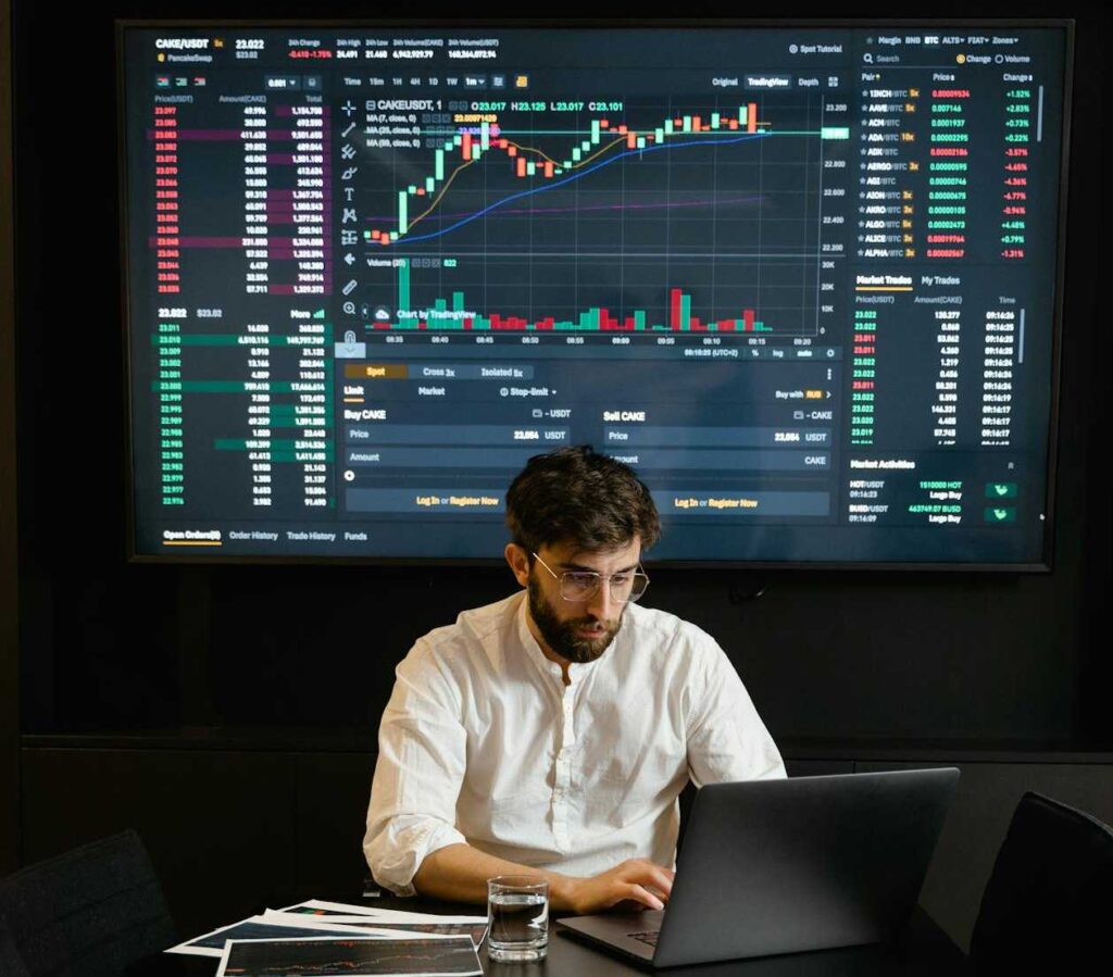 Man working on laptop with board showing dynamic pricing in background